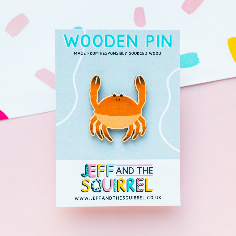 An orange crab shaped wooden pin badge